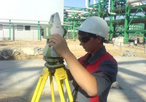Surveyor operating a total station at an industrial site