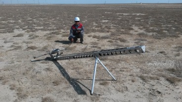 Field worker with a long survey instrument in open terrain