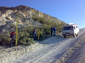 Surveyors and vehicle beside a rocky roadside slope