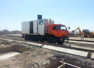 Red survey truck beside industrial rail equipment